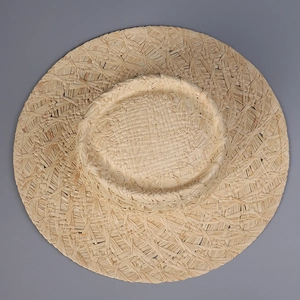 Top down detail of wide brim raffia boater hat with natural straw weaving texture