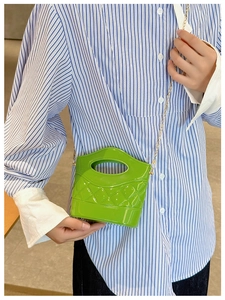 Dettaglio della mini borsa a secchiello verde trapuntata con finitura lucida e catena