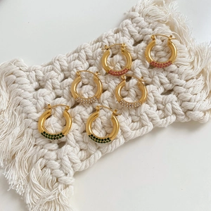 C-shaped gold-plated hoop earrings with colorful zircon inlays on white woven background