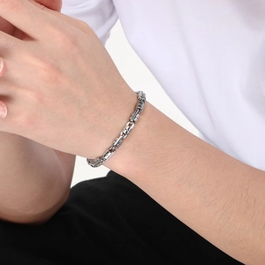 Close-up of a silver Byzantine emperor chain bracelet worn on a male wrist with white shirt