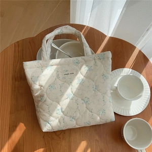 Vue détaillée du sac matelassé en coton floral avec étiquette sur table en bois