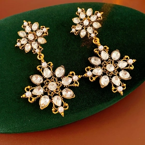Détail de boucles d'oreilles vintage dorées avec fleurs, cristaux et perles sur velours
