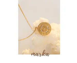 Macro view of 18K gold plated zodiac coin pendant with cubic zirconia on white coral