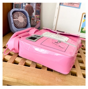 Detail of pink telephone-shaped crossbody bag with glossy finish and receiver handle