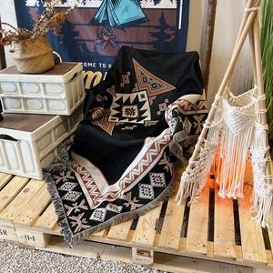 Bohemian geometric tassel camping blanket in black and red weave on wood pallet