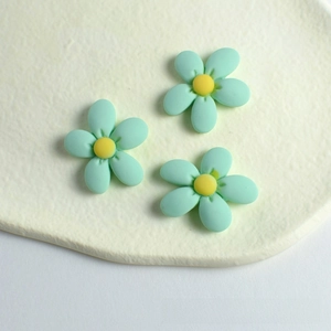 Macro shot of mint green resin peach blossom DIY accessories with yellow centers