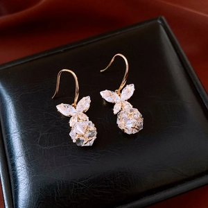 Détail de boucles d'oreilles papillon dorées avec zircons sur boîte à bijoux en cuir noir