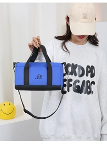 Detail of blue nylon pillow bag featuring black handles and JLP logo on white background