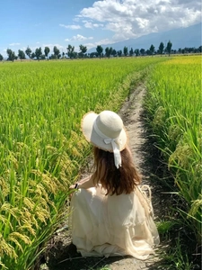 Detail of wide brim straw sun hat with white bow ribbon ribbon against nature background