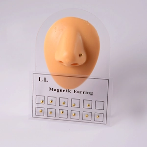 Detail of 12 gold magnetic ball studs on a nose model to show the non-piercing fit