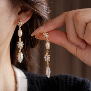 Close-up of elegant vintage tassel earrings with pearls and crystals worn by a model
