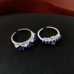 Bagues ouvertes en argent avec zircons bleus ovales et cristaux sur une surface noire mate