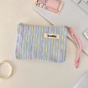 Detail einer hellblauen Stricktasche mit bunten Streifen und rosa Webschlaufe