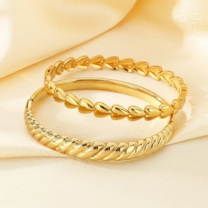 Detailed macro view of heart motif and twisted rope textures on gold stainless steel bracelets