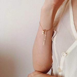 Close-up of gold chain bracelet with letter Z pendant and bar charm on model wrist