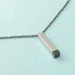 Gros plan d'un pendentif rectangulaire argenté sur une chaîne noire sur fond bleu