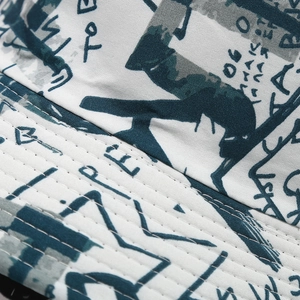 Detailed macro view of graffiti printed fabric and reinforced stitching on a bucket hat