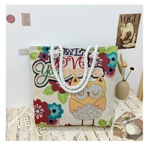 Detailed view of owl embroidery and woven texture on a large beige canvas tote bag