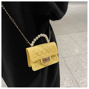 Detail of yellow quilted jelly bag featuring pearl handle and golden chain strap