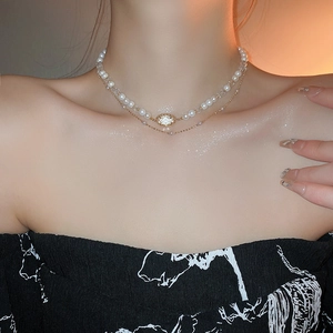 Detail of elegant double-layered necklace with white pearls and gold chain on model