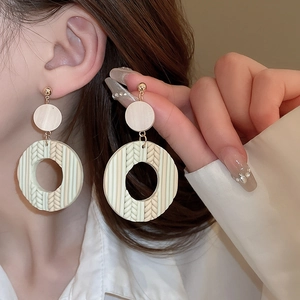 Detail of bohemian round woven drop earrings with beige and brown ethnic textures