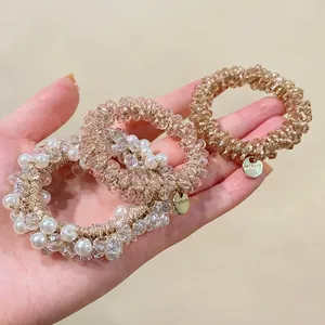Handheld shot of beaded elastic hair ties with faux pearls, crystals and gold tags