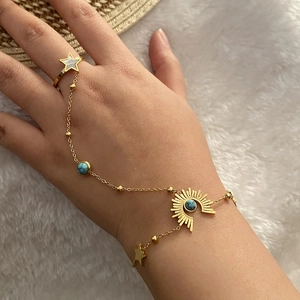 Détail de la bague bracelet dorée avec perles de turquoise et breloques en étoile
