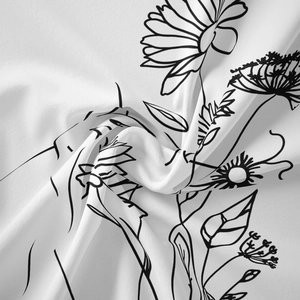 Artistic detail of minimalist black and white floral line art on folded fabric tapestry