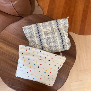 Floral and polka dot pattern canvas cosmetic bags with zippers on a wooden table