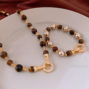 Detailed shot of tiger eye beads and champagne pearls with a zircon-set gold clasp
