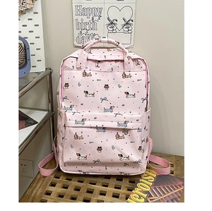 Detailed view of pink backpack with cartoon dachshund dog patterns and blue bows