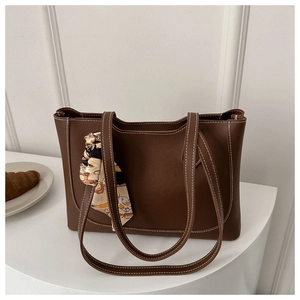 Détail du sac cabas en cuir marron avec surpiqûres blanches et poignée en foulard de soie