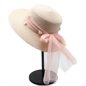 Strohhut mit rosa Band und Perlen auf weißem Grund, Ansicht von oben