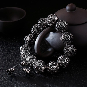 Vintage stainless steel Mantra beads bracelet with bell pendant on a Zen tea table
