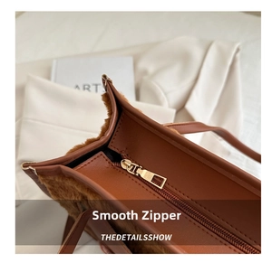 Detail shot of smooth gold zipper and soft brown plush texture on this tote bag