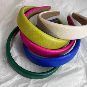 Stack of lychee texture leather headbands in blue, green, and pink on white paper