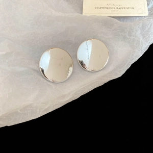 Vue macro de boucles d'oreilles rondes argentées effet miroir sur papier blanc et noir