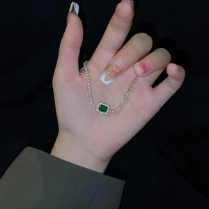 Macro shot of emerald-cut green gemstone bracelet with pavé-set stones on silver chain