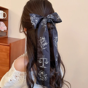Detail of black satin bow hair tie with floral print and long flowing ribbons