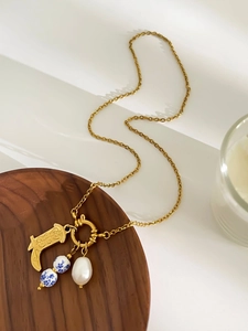 Detail of vintage gold boot pendant with blue porcelain beads and baroque pearl necklace
