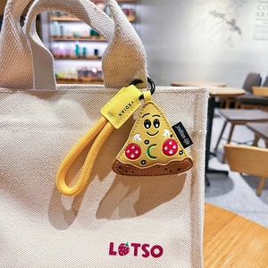 Porte-clés pizza créatif en cuir sur un sac en toile blanche dans un cadre chaleureux