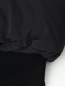 Close-up of black puffer jacket showing ribbed hem detail and high-quality fabric texture
