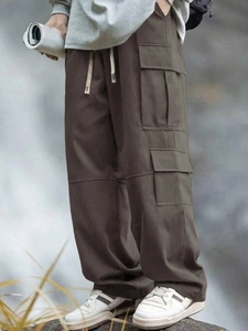 Dettaglio dei pantaloni cargo marroni con tasche funzionali e vita con coulisse