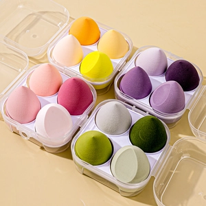 Macro view of four teardrop makeup sponges in a clear box with soft pastel colors