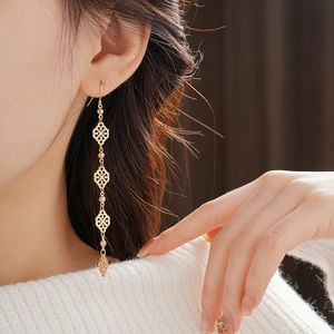 Detail of elegant gold long earrings featuring hollow four-leaf clover patterns and rhombus