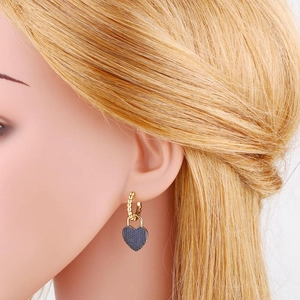 Close-up of a blue heart padlock earring with gold hoop on a model's ear