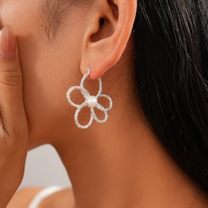 Detail von silbernen hohlblüten-ohrringen mit perle am ohrläppchen des models