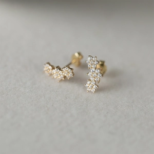 Macro detail of gold flower stud earrings with sparkling cubic zirconia clusters