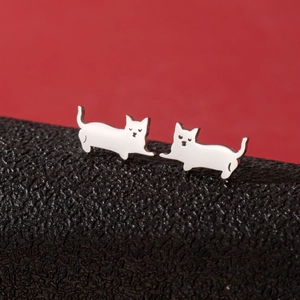 Macro view of silver stainless steel cat earrings on red and black background