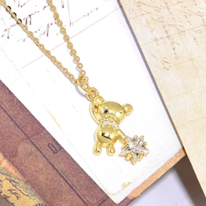 Golden necklace with a zircon-encrusted bear pendant holding a star on vintage envelope